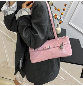Detail of pink glossy shoulder bag with silver heart pendant and buckle decoration