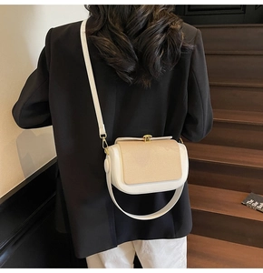 Detail of a chic cream and camel color-block saddle bag with metallic gold clasp