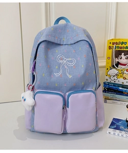 Detail of blue plaid school backpack with purple pockets and a cloud plush pendant