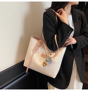 Detail of off-white lychee leather tote bag with pink straps and cute bear pendant charm