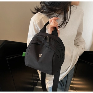Detail of black nylon shell bag with metal logo, green tag and side view on model