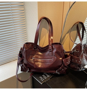 Detail of burgundy tote bag with metallic rivets, zipper pockets and glossy PU texture