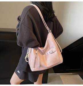 Detailed view of pink hobo bag with metal buckle pocket and woven tassel zipper accessory