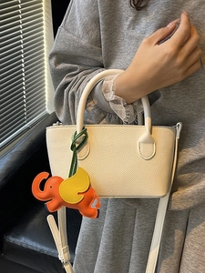 Minimalist cream lychee-grain bucket bag with a cute elephant leather charm accessory