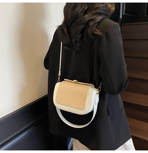 Detail of elegant two-tone crossbody bag with textured flap and gold square lock