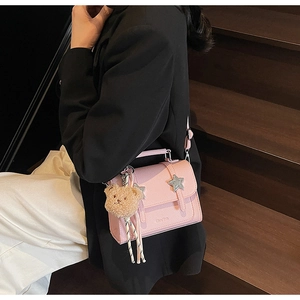 Détail du sac bandoulière en cuir rose avec pendentif ours et clous en étoile