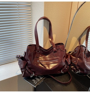 Detailed view of large dark red tote bag with multiple pockets and polished leather texture