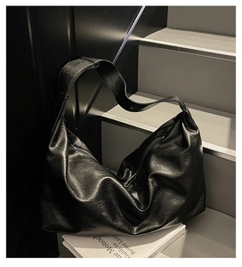 Detail of black pebbled leather tote bag with silver zipper on a staircase