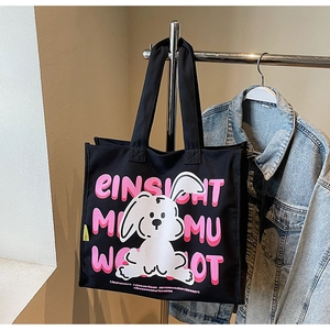 Detail of black canvas tote bag with cartoon rabbit print and pink lettering on hanger