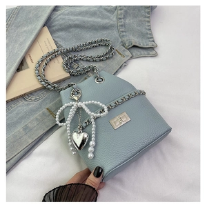 Detail of light blue lychee leather bucket bag with pearl bow and heart charm