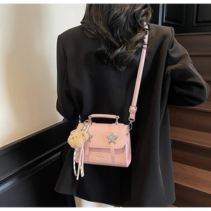 Détail du sac à bandoulière en similicuir rose avec étoiles et breloque ours brun