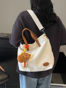 Minimalist white canvas tote bag with brown leather handles and bear pendant for women