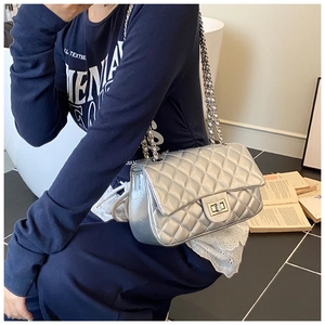 Close-up of silver quilted chain bag with metallic texture and turn-lock on shoulder