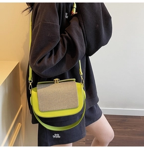 Close-up of contrast stitching on a lime green saddle bag with textured grey flap and gold clasp