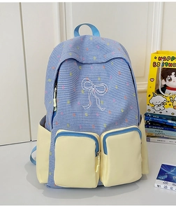 Detail view of preppy style color-block backpack with bow pattern and functional pockets
