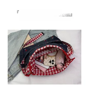 Detail of blue denim bucket bag showing large capacity storage and cherry embroidery