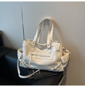 Close-up of cream tote bag featuring multiple pockets, metal buckles and zip details