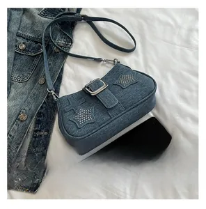 Detailed view of blue denim shoulder bag with star rivets and cross pattern on white fabric