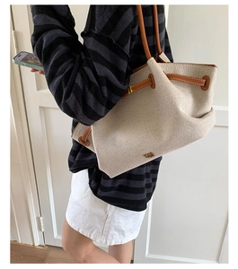 Close-up of vintage canvas tote bag with brown leather handles and gold logo detail