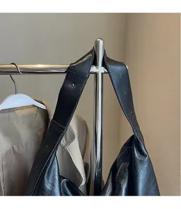 Detail of adjustable wide shoulder strap and soft leather texture on black tote bag