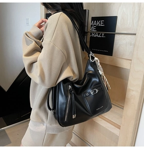 Detail view of large matte black tote bag with buckle pocket and silver branding