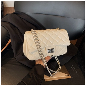 Detail of cream quilted bag with silver twist lock and woven metal chain strap