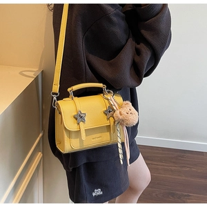 Détail du sac jaune à motif litchi avec boucle étoile et breloque ours en peluche