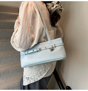 Close-up of light blue leather underarm bag with silver heart pendant and metal buckle