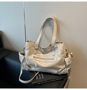 Detail of cream functional tote bag with utility side pockets and metal buckles