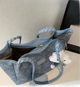 Detail of floral denim tote bag with woven handles and smooth silver metal zipper close-up