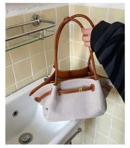 Detalle del bolso tote de lona y cuero marrón con cordón y herrajes dorados elegantes