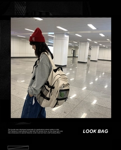 Détails des boucles latérales et de la poche filet sur le sac à dos crème spacieux