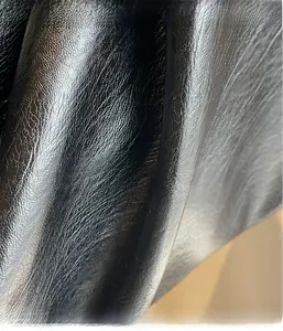 Detail of soft black pebbled leather texture on a large minimalist tote handbag