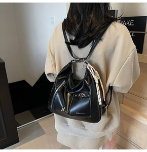 Detail of a black synthetic leather tote bag showing unique drawstrings and branding