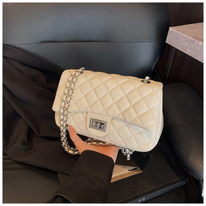 Detailed macro view of cream quilted faux leather texture with silver chain and twist lock
