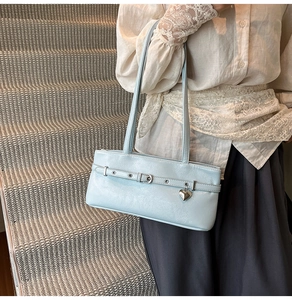 Close-up of light blue shoulder bag featuring silver heart pendant and glossy texture