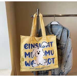 Detailed view of yellow canvas tote bag featuring cute cartoon rabbit and typography