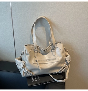 Close-up of cream utility tote bag featuring multi-pocket design and soft faux leather texture