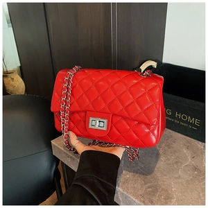 Detailed close-up of bright red quilted crossbody bag with silver chain and metal lock