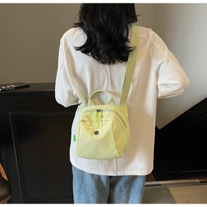 Detail of light green nylon mini backpack with adjustable straps shown on model back