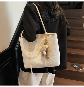 Vista dettagliata della borsa tote bianca testurizzata con motivo 3D a rilievo e ciondolo orsetto
