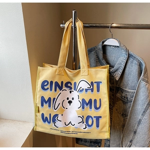 Close-up of yellow canvas tote bag with white cartoon rabbit and blue letter printing