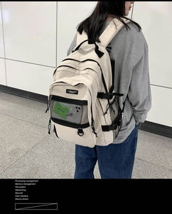 Détail du sac à dos en nylon crème avec poche filet avant et boucle latérale réglable