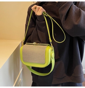 Detail of green leather crossbody bag with beige textured flap and gold metal buckle