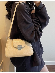 Chic beige underarm bag with glossy pleated texture and silver metal buckle on model