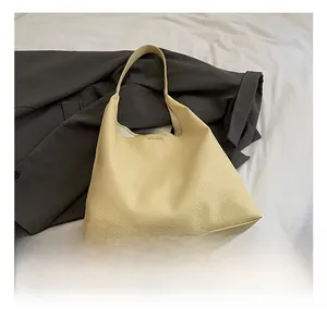 Detail of lychee textured leather on light yellow hobo shoulder bag with wide strap