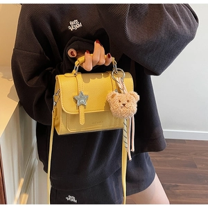 Détail du sac à main jaune grainé avec ornement étoile et breloque ours en peluche
