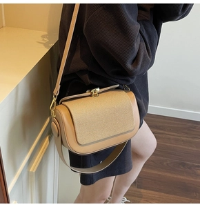 Detail of retro small square bag showing woven texture cover and gold metal swivel clasp