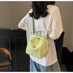 Detail view of a light green nylon shell bag worn as a shoulder bag on a model
