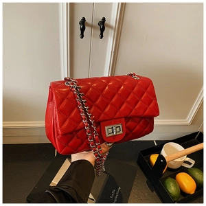 Detail of red quilted shoulder bag with glossy finish and silver chain strap